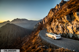 Tesla Model 3 – rear three-quarter, white against a mountain backdrop