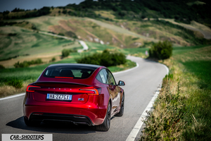 Tesla Model 3 Performance – rear three-quarter, red metallic on a winding country road